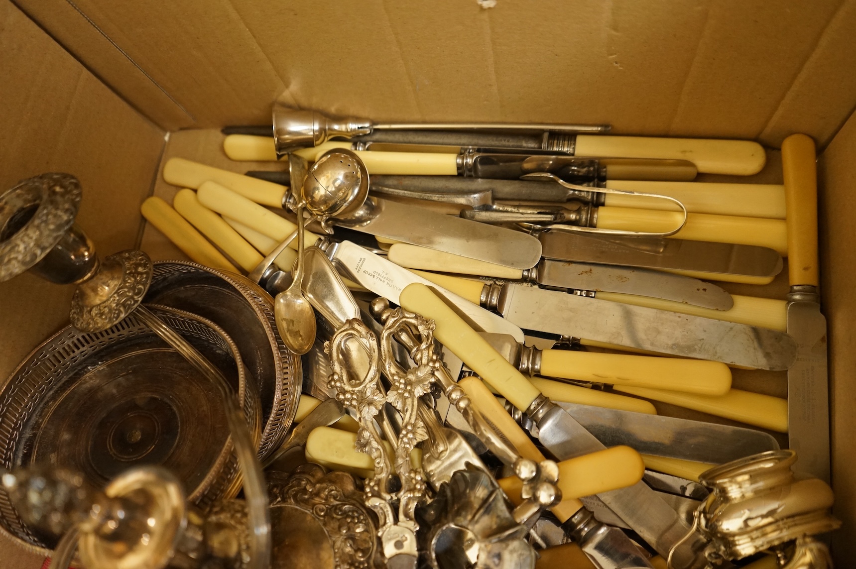 A group of sundry plated items including dwarf candelabra, a pair of wine coasters, a pair of grape shears, etc., and a quantity of assorted ivorine handled table and dessert knives.